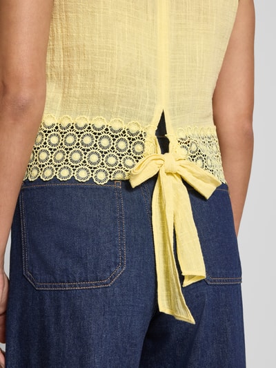 Frauenmodel trägt Regular Fit Top mit Lochstitching von Apricot in Gelb, Reine Baumwolle, Zierschleife, Detailaufnahme Rücken.