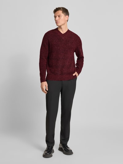 Männermodel trägt Relaxed Fit Strickpullover mit Alpaka-Anteil Modell 'FLOYD' von Samsøe Samsøe in Bordeaux, Ganzkörperansicht von vorne, Herren Strickpullover im Woll-Mix mit V-Ausschnitt, strukturierte Oberfläche.