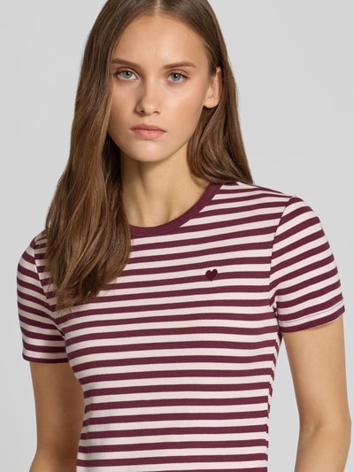 Kobiece model nosi t-shirt Slim Fit T-Shirt aus Baumwoll-Mix model 'VAL' od ONLY, biało-bordowe paski, faktura prążkowana, zbliżenie na górną część ciała.