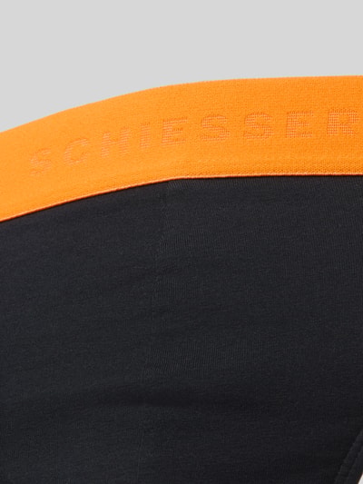 Männermodel trägt Slip mit elastischem Bund im 3er-Pack von Schiesser, Baumwoll-Elasthan-Mix, schwarze Farbe, Nahaufnahme Oberkörper.