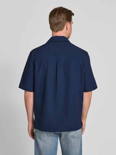 Männermodel trägt Relaxed Fit Freizeithemd aus Seersucker-Material von Tommy Hilfiger, Optik:Allover-Muster, Kellerfalte, Kurzarm, Rückenansicht.
