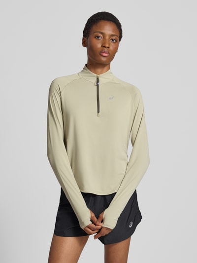 Frauenmodel trägt Longsleeve mit Troyer-Kragen Modell 'NAGINO' von ASICS TIGER in Beige, reflektierender Logo-Print, Ganzkörperansicht von vorne.