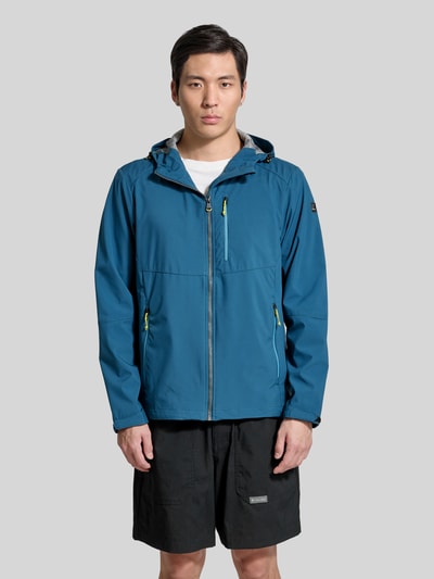 Männermodel trägt Regular Fit Jacke mit Logo-Applikation von Killtec in Blau, Kapuze, Napoleontasche und Reißverschlusstaschen, Ganzkörperansicht von vorne.