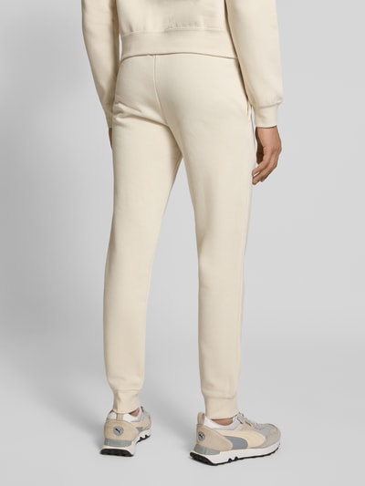 Männermodel trägt Sweatpants mit Label-Stitching von PUMA PERFORMANCE aus Baumwoll-Mix, Regular-Fit, cremefarben, Ganzkörperansicht Rückansicht.