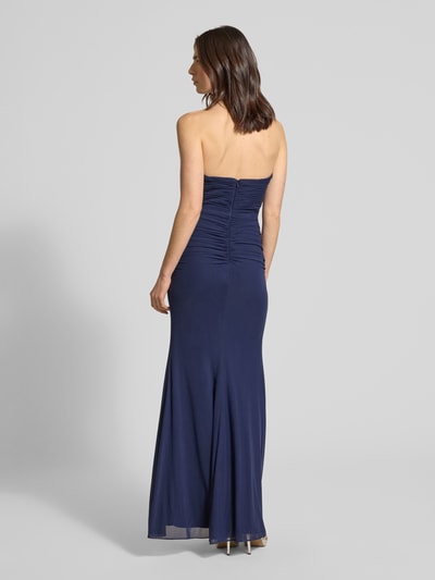 Modelka nosi Regular Fit Abendkleid mit Gehschlitz von Luxuar, półprzezroczysty materiał, krój regular fit, rozporek, taliowany, wszyty zamek błyskawiczny, halka pod spódnicę, długość tyłu w rozmiarze 36: 132 cm, szerokość w rozmiarze 36: 38 cm, widok całej sylwetki z tyłu.