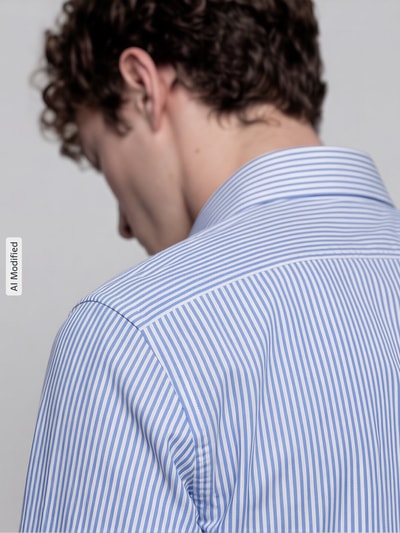 Männermodel trägt Slim Fit Business-Hemd mit Kentkragen von Jake*s in Hellblau-Weiß mit feinem Streifenmuster, Detailaufnahme Rückansicht, reine Baumwolle, Knopfleiste, Rückenlänge 79 cm, Schulterbreite 46 cm, Ärmellänge 66 cm.