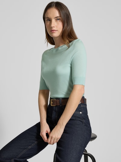 Modelka kobieca ma na sobie Slim Fit Pullover aus reiner Schurwolle Modell 'FARBELLA' od BOSS, miękki jasnomiętowy, krój slim fit, półrękaw, okrągły dekolt, gładka faktura wełny, detale prążkowane, widok z przodu do połowy sylwetki.