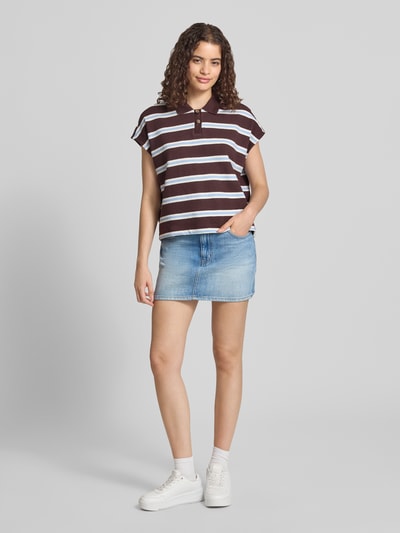 Frauenmodel trägt Regular Fit Poloshirt aus reiner Baumwolle von Marc O'Polo DENIM, braun-weiß gestreift, zu Jeansrock, Ganzkörperansicht von vorne.