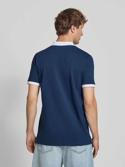 Männermodel trägt Regular Fit Poloshirt mit Label-Stitchings von ellesse in donkerblauw en wit, Puur katoen, Knoopsluiting, Ganzkörperansicht Rückansicht. Ruglengte bij maat M: 77 cm