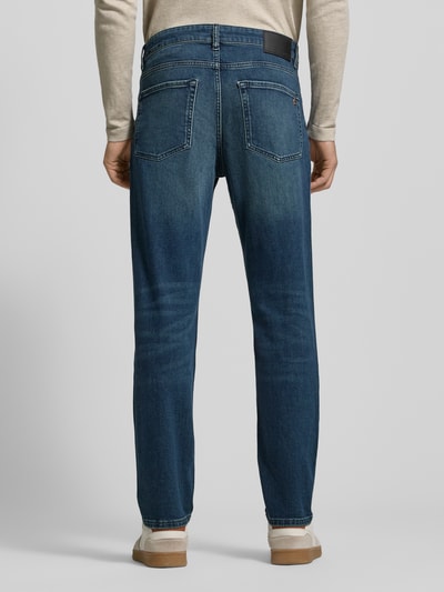 Männermodel trägt Slim Fit Jeans aus Baumwoll-Mix Modell 'SMU ONYX' von BOSS Orange, Denim-Optik, Label Patch, Rückansicht.