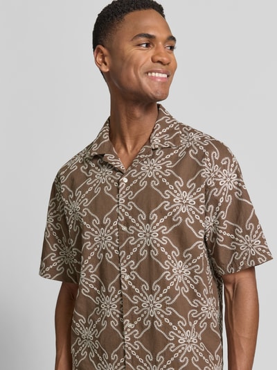 Mannelijk model draagt Regular Fit vrijetijdsoverhemd uit mix van linnen en katoen met stitchings, reverskraag, 1/2-mouwen van MCNEAL, bruine kleur met wit patroon, nahaufnahme bovenlichaam. Context: ruglengte maat M 71 cm, schouderbreedte 46 cm, mouwlengte 26 cm.