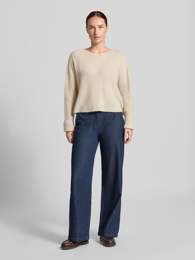 Frauenmodel trägt Strickpullover aus Alpaka-Mix Modell 'MENY' von DRYKORN, locker geschnitten, beige Farbe, weiche Textur, Ganzkörperansicht von vorne.