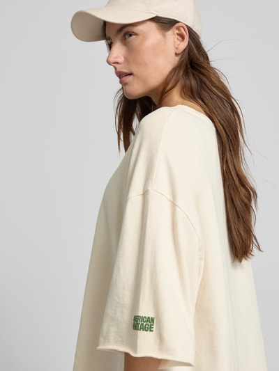 Frauenmodel trägt Oversized T-Shirt mit Label-Print von American Vintage aus reiner Baumwolle, cremefarben, Nahaufnahme Oberkörper.