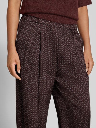 Frauenmodel trägt Loose Fit Weite Hose mit Allover-Muster von Jake*s Collection, dunkle Töne, kleine Muster, Nahaufnahme Oberkörper.