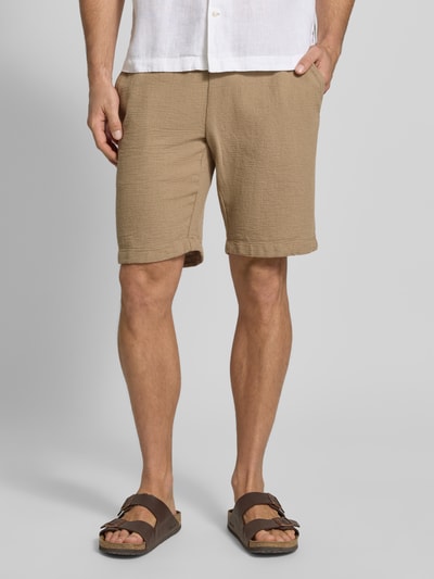 Männermodel trägt Shorts mit elastischem Bund und Tunnelzug von MCNEAL aus Baumwoll-Mix, Regular-Fit, beiger Ton, Nahaufnahme Unterkörper.