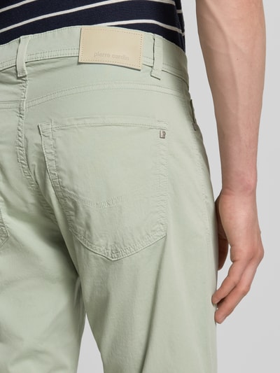 Mężczyznamodel nosi Regular Fit Hose mit Eingrifftaschen Modell 'Lyon' von Pierre Cardin, mieszanka bawełny i elastanu, wpuszczane kieszenie, krój regular fit, szerokość w rozmiarze 32/32: 43 cm, długość wewnętrzna nogawki 79 cm, jasny zielony, struktura gładka, detal tylnej kieszeni, zbliżenie tyłu.