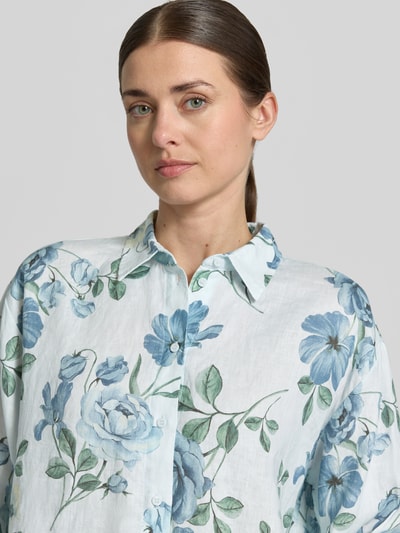 Modelka nosi Regular Fit Hemdbluse aus Leinen od Jake*s Collection, czysta len, krój regular fit, kołnierz kent, guziki, obniżone ramiona, długość pleców w rozmiarze 36: 64 cm, długość rękawa w rozmiarze 36: 57 cm, biały materiał z niebieskimi i zielonymi kwiatami, tekstura lniana, zbliżenie górnej części ciała.