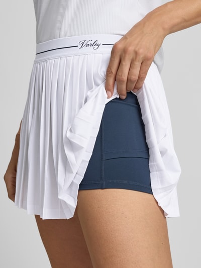 Frauenmodel trägt weißen Minirock mit integrierten Shorts Modell 'Clemency' von VARLEY, elastischer Bund, leichte A-Linie, Logo-Stitching, Nahaufnahme Oberschenkel.