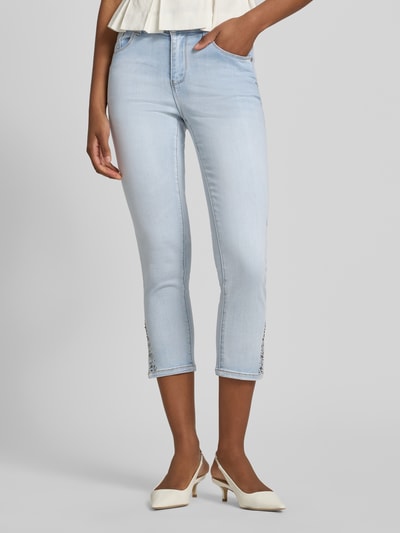 Frauenmodel trägt Slim Fit Jeans mit Viskose-Anteil in verkürzter Passform von Betty Barclay im hellblauen 5-Pocket-Design, Ganzkörperansicht von vorne. Elastischer Baumwoll-Mix mit Viskose-Anteil, Knopf- und Reißverschluss, Bundweite bei Größe 36: 35 cm, Innenbeinlänge bei Größe 36: 64 cm.