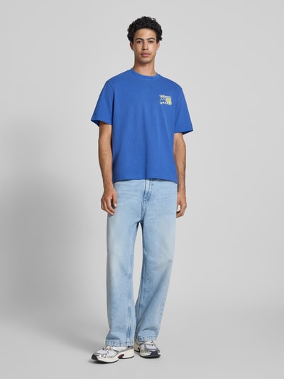 Männermodel trägt Regular Fit T-Shirt aus reiner Baumwolle Modell '90s' von Tommy Jeans, Optik: Unifarben, Label-Print, Ganzkörperansicht von vorne
