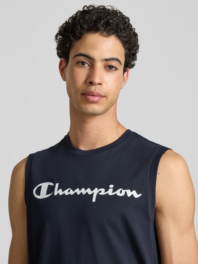 Mannelijk model draagt Top met Logo en Rundhalsausschnitt van CHAMPION in katoenmix, regular fit, marineblauw, logo, close-up bovenlichaam.