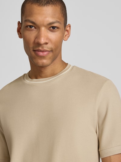 Männermodel trägt Regular Fit T-Shirt aus reiner Baumwolle Modell 'C-TAUT-40' von BOSS in Beige, Piqué-Struktur, Nahaufnahme Oberkörper.