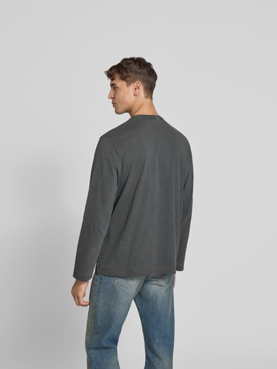 Männermodel trägt Relaxed Fit Longsleeve aus Baumwolle von Forét in Grau mit Used-Look, Label-Stitching, Rückenlänge 71 cm, Ganzkörperansicht Rückansicht.