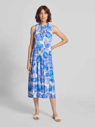 Frauenmodel trägt Midikleid aus Viskose Modell 'Vi44vii' von ZABAIONE in Weiß mit blauem Allover-Print, A-Linie, Stehkragen und Schnürung, Ganzkörperansicht von vorne.