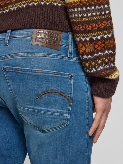 Männermodel trägt Skinny Fit Jeans im Used-Look Modell 'REVEND' von G-Star Raw, mieszanka bawełny, krój skinny fit, efekt znoszenia, szerokość w pasie 42 cm, długość wewnętrzna nogawki 79 cm, Ganzkörperansicht Rückansicht.