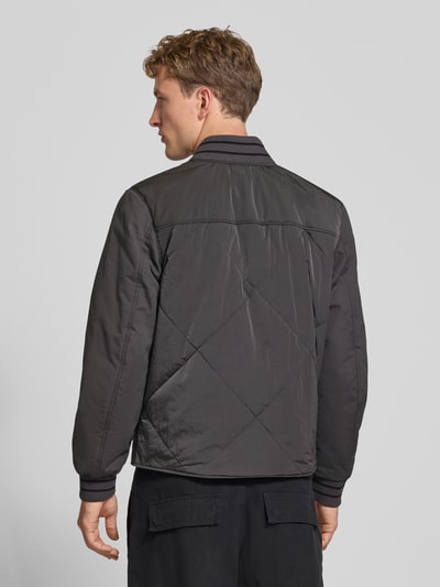 Männermodel trägt Relaxed Fit Bomberjacke aus reiner Baumwolle von Calvin Klein Jeans in dunklem Grau, glatte Oberfläche, Ganzkörperansicht Rückansicht, Herren Bomberjacke / Blouson.