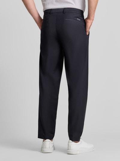 Mężczyzna nosi spodnie Loose Fit Hose mit Bügelfalten Modell 'Lexter' von JOOP! z mieszanki materiałów z dodatkiem wełny, kolor ciemny, kanty, krój loose fit, szerokość w rozmiarze 50: 46 cm, długość wewnętrzna nogawki w rozmiarze 50: 80 cm, kolekcja JOOP! COLLECTION, Ganzkörperansicht Rückansicht.