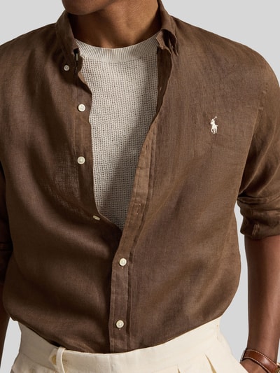 Mannenmodel draagt Slim Fit vrijetijdsoverhemd uit puur linnen van Polo Ralph Lauren, effen kleuren, logodetail, gevlamd garen, knoopsluiting, button-downkraag, lange mouw, licht afgeronde rompzoom, detailopname bovenlichaam.