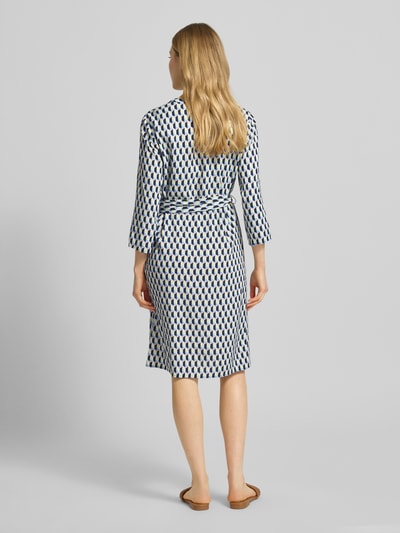 Frauenmodel trägt Regular Fit Midikleid aus reiner Viskose von Betty Barclay mit geometrischem Allover-Print, 7/8-Arm, Stoffband, Ganzkörperansicht Rückansicht.