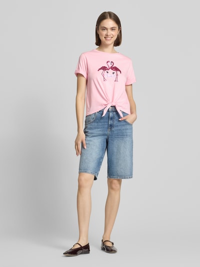 Frauenmodel trägt Slim Fit T-Shirt aus Baumwoll-Mix Modell 'MIRA' von Only in Rosa, unifarben mit Flamingo-Print, Jersey-Textur, Ganzkörperansicht von vorne.