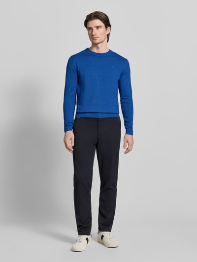 Männermodel trägt Regular Fit Strickpullover aus reiner Baumwolle von Tom Tailor in Optik: Unifarben mit Logo-Stitching, Ganzkörperansicht von vorne.