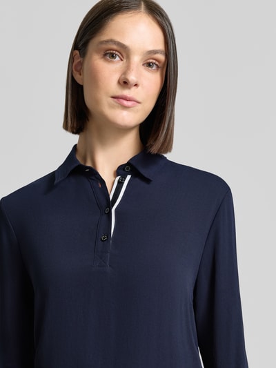 Kobieta nosi Regular Fit koszulkę polo z elastycznymi zakończeniami rękawów Marc Cain, kołnierzyk polo, z długim rękawem, długość tyłu w rozmiarze 36: 63 cm, zbliżenie na górną część ciała.