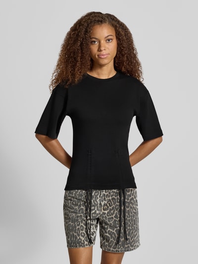 Modelka prezentuje damski t-shirt z bawełny, prosty krój, model 'MALLE' od Topshop, okrągły dekolt, marszczenia z wiązaniem, długość tyłu 66 cm w rozmiarze S, ciemny kolor, gładka faktura, całkowity widok z przodu.