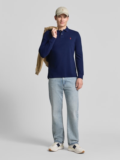 Männermodel trägt Regular Fit Poloshirt aus reiner Baumwolle von Polo Ralph Lauren in Optik: Unifarben, Passform: Regular-Fit, Applikation: Logo-Stitching, Kragenform: Polokragen, Ausschnitt: V-Ausschnitt, Verschluss: kurze Knopfleiste, Ärmelform: Langarm, Materialverarbeitung: Piqué, Material: reine Baumwolle, Ganzkörperansicht von vorne.