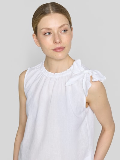 Frauenmodel trägt Regular Fit Bluse aus Viskose-Mix mit Leinen-Anteil von Christian Berg Woman in Weiß mit Zierschleife, Stehkragen mit Rüschenbesatz und Ärmelloses-Design, Rückenlänge bei Größe 36: 54 cm, Nahaufnahme Oberkörper.