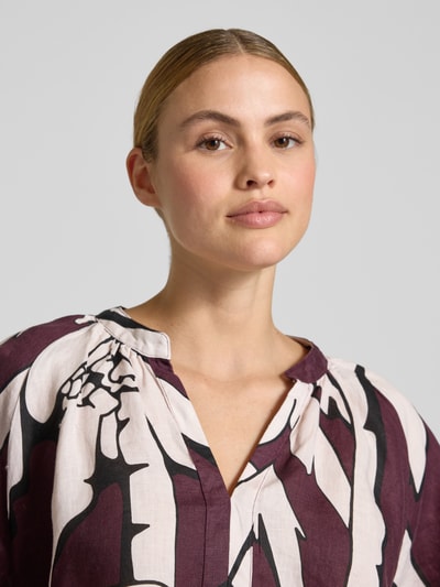 Frauenmodel trägt Boxy Fit Leinenbluse im Allover-Look von Christian Berg Woman, V-Ausschnitt, Muster in Weiß, Lila, Schwarz, Nahaufnahme Oberkörper.