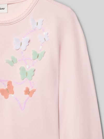 Mädchen trägt Regular Fit Langarmshirt aus Baumwoll-Mix von s.Oliver RED LABEL, pastellrosa, Schmetterlings-Applikation, Effektgarn, Nahaufnahme Oberkörper.