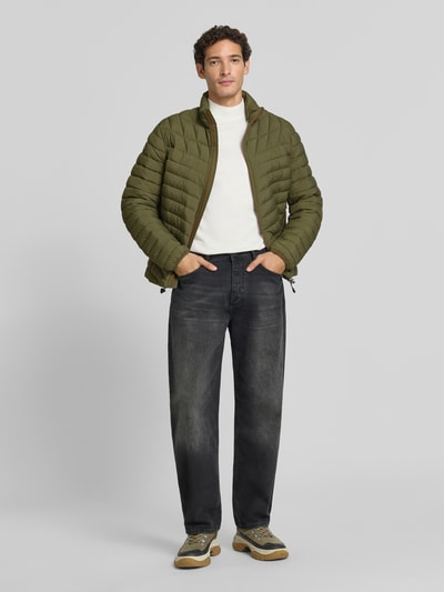 Männermodel trägt Steppjacke mit Label-Patch Modell 'LAPAZ' von Napapijri in Oliv, gerader Schnitt, seitliche Reißverschlusstaschen, Ganzkörperansicht von vorne.