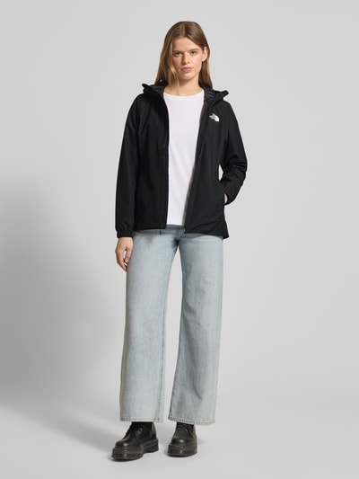 Modelka nosi Regular Fit Jacke mit Logo-Print von The North Face, czarna, kaptur, zamek, kieszenie, krój regular fit, długość tyłu 68 cm, szerokość ramion 37 cm, szerokość klatki 34 cm, długość rękawa 62 cm, zdjęcie całej sylwetki z przodu.