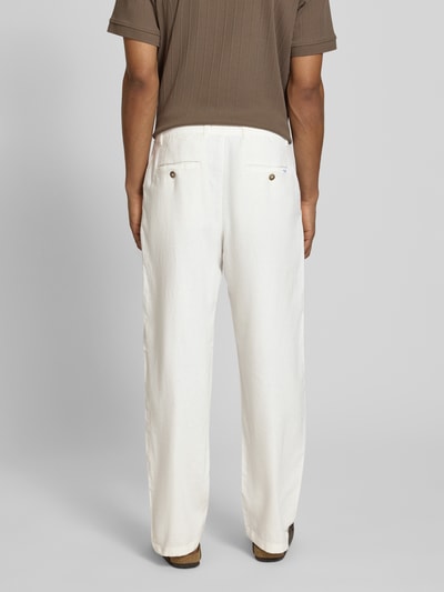 Männermodel trägt Loose Fit Hose aus Baumwoll-Leinen-Mix Modell 'BRODY' von SELECTED HOMME in creme, Struktur-Flammgarn, Ganzkörperansicht Rückansicht.