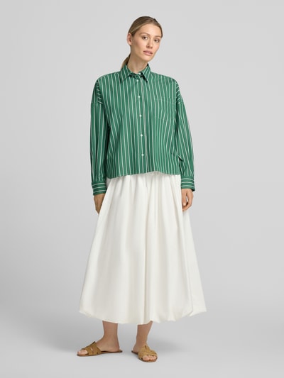 Vrouwenmodel draagt groene blouse met lange mouwen regular fit van puur katoen model 'ONORE' van Weekend Max Mara, witte rok, sandalen, geheellichaamsaanzicht van voren.