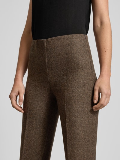 Frauenmodel trägt Straight Fit Stoffhose aus Woll-Mix Modell 'Piper' von Mango in Braun mit Bügelfalte, elastischer Bund, Nahaufnahme Oberkörper. Damen Stoffhose geeignet für Größe 36, Bundweite 35 cm, Innenbeinlänge 83 cm, texturierte Optik.