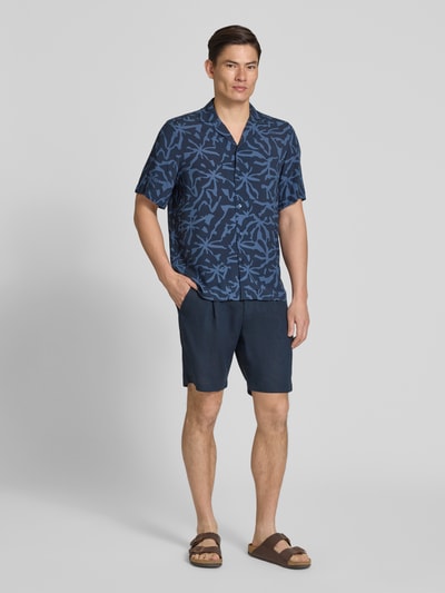 Męski model nosi Regular Fit Freizeithemd aus Viskose Modell 'RAYER_M' od BOSS Orange, ciemnoniebieski z nadrukiem allover, krój regular fit, resortowy kołnierz, krótkie rękawy, czysta wiskoza, widok całej sylwetki z przodu.