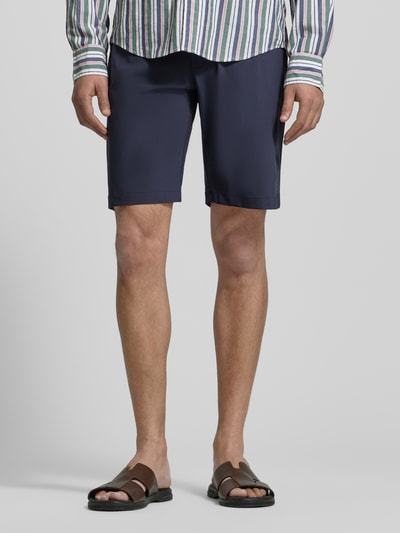 Mężczyzna nosi Straight Fit Shorts mit elastischem Bund von CRUNA, granatowy kolor, kieszenie z tyłu, wygodny elastyczny pas, długość do kolan, Szerokość w rozmiarze 50: 42 cm, Długość wewnętrzna nogawki w rozmiarze 50: 26 cm, Ganzkörperansicht z przodu.