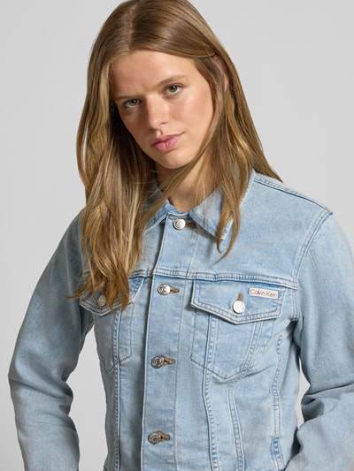 Kobieta modelka ma na sobie Relaxed Fit Jeansjacke aus reiner Baumwolle od Calvin Klein Jeans, jasnoniebieska kurtka jeansowa, tekstura bawełniana, widok z przodu, zbliżenie na górę ciała.