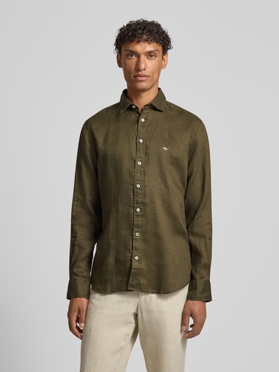 Męskimodel nosi Slim Fit Leinenhemd mit Haifischkragen von Fynch-Hatton, len, krój slim fit, wyhaftowane logo, kołnierzyk typu cutaway, długość tyłu 77 cm, szerokość w rozmiarze M 47 cm, długość rękawów 61 cm, oliwkowozielony, gładka faktura, ganzkörperansicht z przodu.